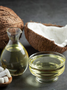 A jug of coconut oil whit coconut put on dark background. By Aura Pure Oils.